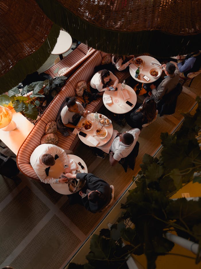 Aerial shot capturing people dining in a trendy Parisian restaurant, emphasizing social interactions.