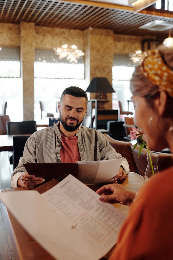 A couple browsing menus at a cozy restaurant, showcasing a modern interior and casual atmosphere.
